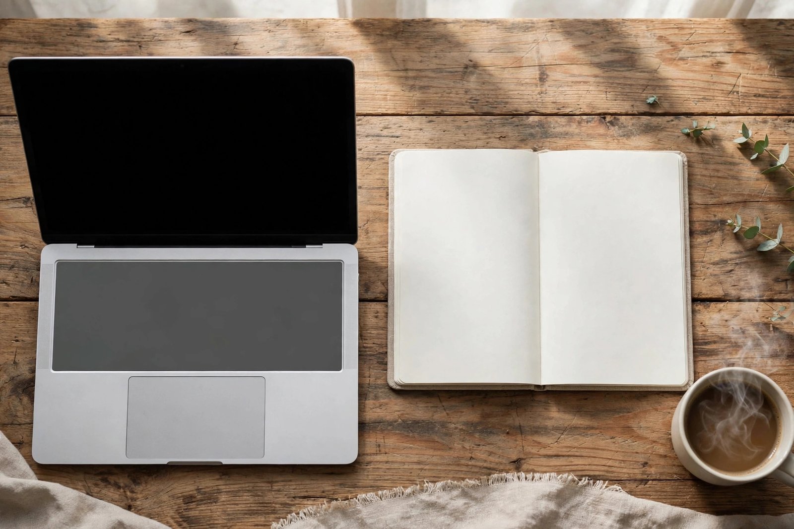  "Laptop with blank screen beside a blank notebook and coffee on a wooden desk"